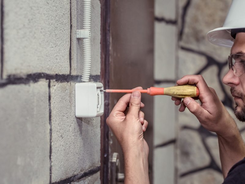 male electrician-technician, connects the equipment with a tool, the concept of the installer's work, space for text